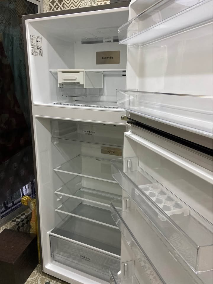 Open LG 343 L refrigerator showing storage organiser layout with glass shelves, door bins, top freezer section and Fresh Zone drawer